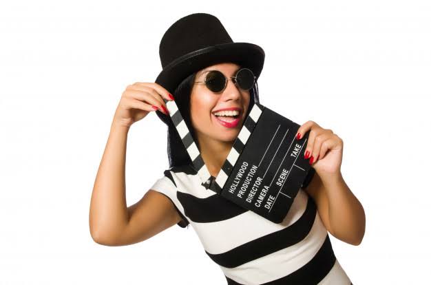 Person in a black and white outfit holding a movie clapperboard