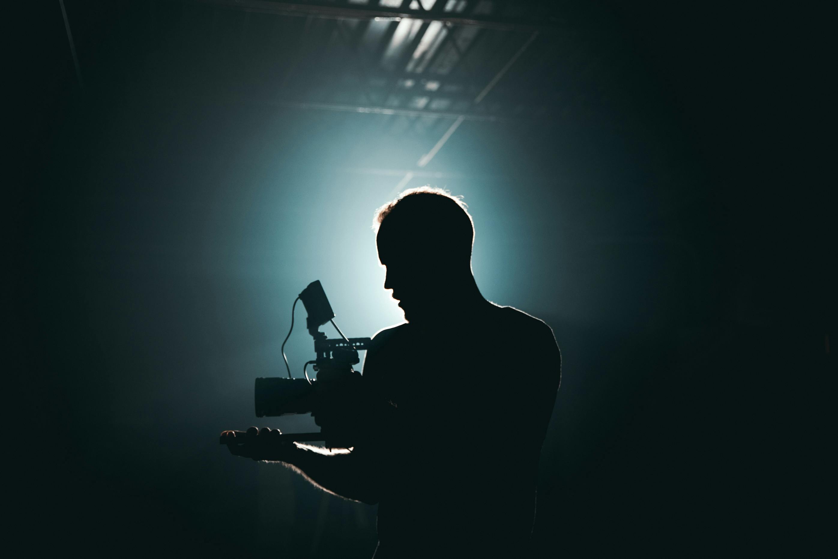 Silhouette of a person holding a camera backlit by a strong light source